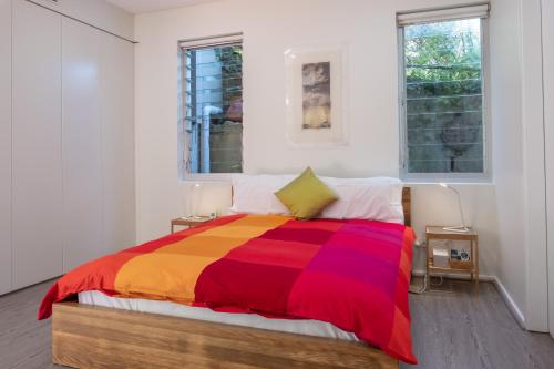 een slaapkamer met een kleurrijk bed en 2 ramen bij Bondi Lock-Down Retreat, The Cute Place To Put Up Your Feet in Sydney