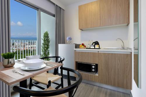 a kitchen with a table and chairs and a kitchen with a window at Centre Point Prime Hotel Pattaya in Pattaya North