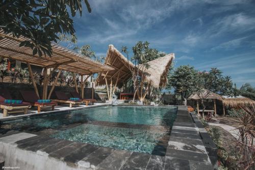 uma piscina num resort com cadeiras e guarda-sóis em Menjangan Hill em Banyuwedang