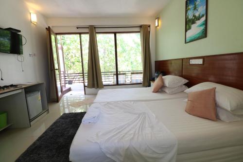 a bedroom with two beds and a large window at Liberty Guesthouse Maldives in Mahibadhoo