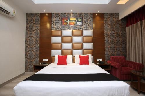 a bedroom with a large bed and a red chair at Hotel Shagun Chandigarh Zirakpur in Chandīgarh