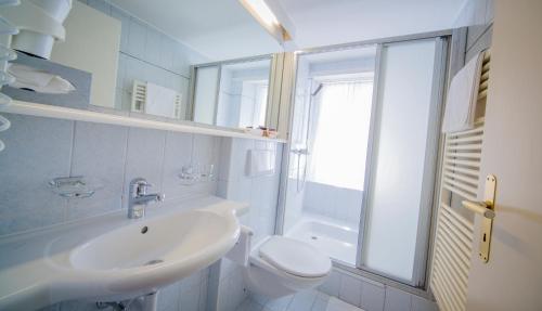a white bathroom with a sink and a toilet at Hotel Heilquelle in Leukerbad