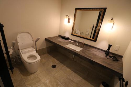 a bathroom with a toilet and a sink and a mirror at Yado Hanasaku in Tateyama