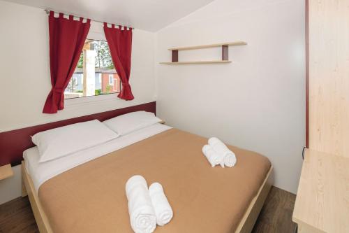a bedroom with a bed with white slippers on it at Camping Park Umag Mobile Homes in Umag