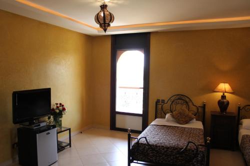 a bedroom with a bed and a tv and a window at Palais Dar Ouladna in Marrakech