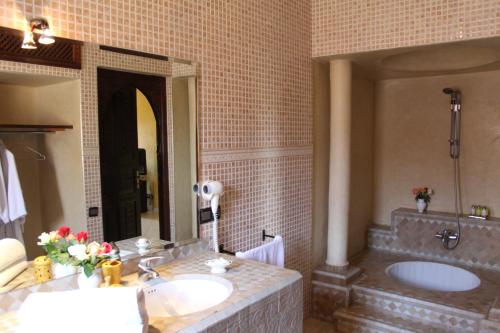 a bathroom with a sink and a tub and a mirror at Palais Dar Ouladna in Marrakech