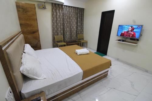 a bedroom with a bed and a flat screen tv at Green Arc Homestay in Malvan
