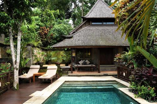 a swimming pool in front of a house with a resort at Ibah in Ubud