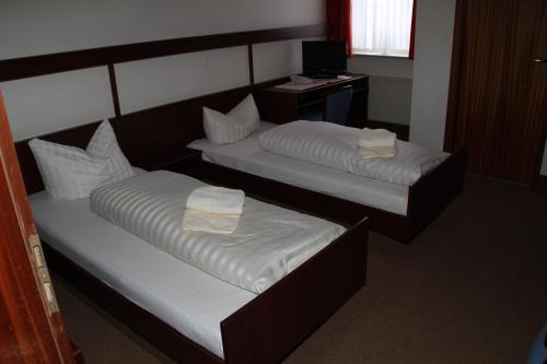 two beds with white sheets and a desk in a room at Einfelder Hof garni in Neumünster