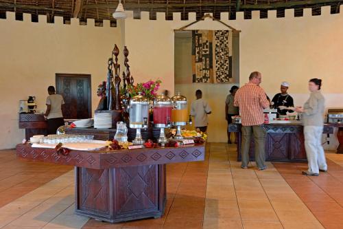 eine Gruppe von Menschen steht mit Essen um einen Tisch herum in der Unterkunft Ocean Paradise Resort & Spa in Pwani Mchangani