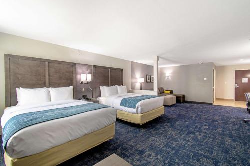 a hotel room with two beds and a room with two tables at Comfort Suites Humble Houston IAH in Humble