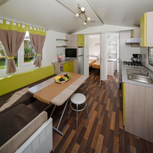 a kitchen and living room with a table and a dining room at Camping Park Umag Mobile Homes in Umag