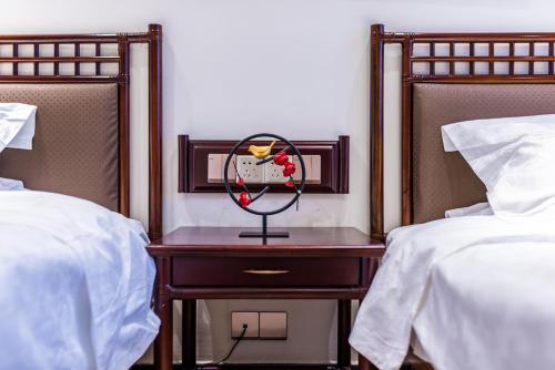 a clock on a table between two beds at Hainan Jingshan Hotel in Haikou