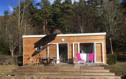 a tiny house with a table and chairs on a deck at Camping Domaine du Lac Chambon in Murol