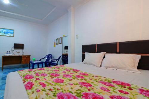 um quarto com uma cama grande com flores cor-de-rosa em Hotel Rembulan em Tebingtinggi