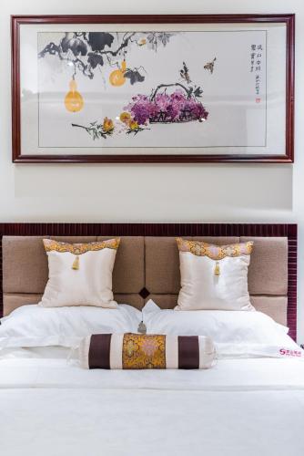 a bed with two pillows and a picture on the wall at Hainan Jingshan Hotel in Haikou