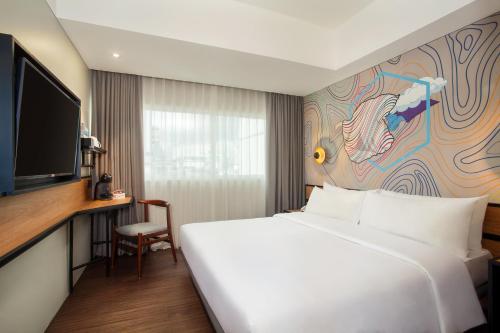 a hotel room with a white bed and a tv at Swiss-Belinn Wahid Hasyim in Jakarta