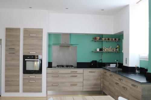 - une cuisine avec des placards en bois et des murs verts dans l'établissement Maison Cahors, à Cahors