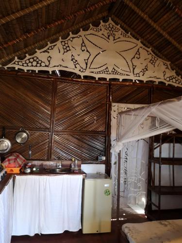 una cucina con un tavolo in una stanza con un soffitto di CHEZ ALEX a Nosy Be