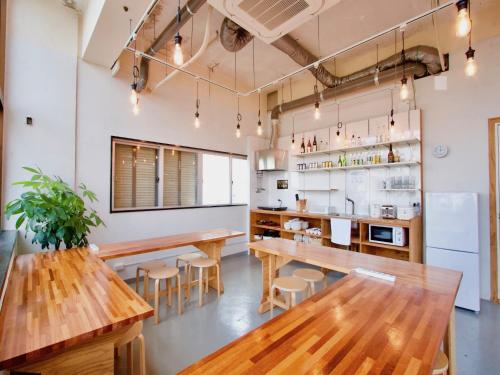 a large kitchen with wooden tables and stools at Ishigaki Guesthouse HIVE in Ishigaki Island