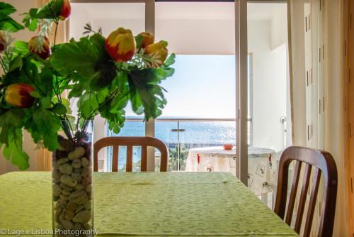 een tafel met een vaas met bloemen erop bij Apt Baleeira Sol in Albufeira