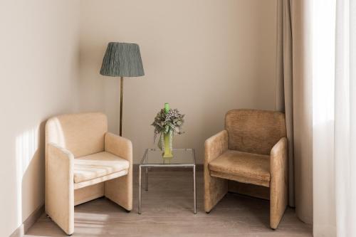 two chairs and a table with a vase of flowers at Villa Cavalletti in Grottaferrata