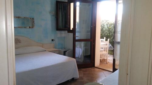 Schlafzimmer mit einem Bett und einer Tür zu einem Balkon in der Unterkunft Hotel Sa Cralla in Villasimius