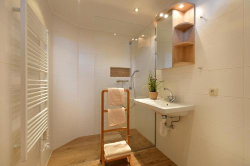 La salle de bains blanche est pourvue d'un lavabo et d'un miroir. dans l'établissement Haus Alpenrose, à Scheffau am Wilden Kaiser