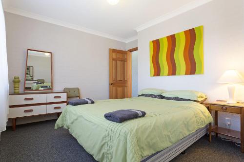a bedroom with a bed and a dresser and a mirror at Pacific Pines Unit 6 in Narooma