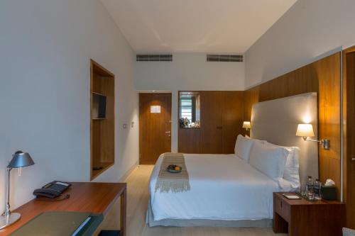 1 dormitorio con 1 cama blanca grande y escritorio en The Manor - New Delhi, en Nueva Delhi