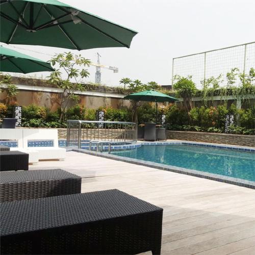 a swimming pool with tables and umbrellas in a building at ibis Styles Cikarang in Cikarang