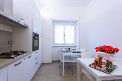 una cocina con armarios blancos y una mesa con flores rojas en Elements Guest House, en Roma
