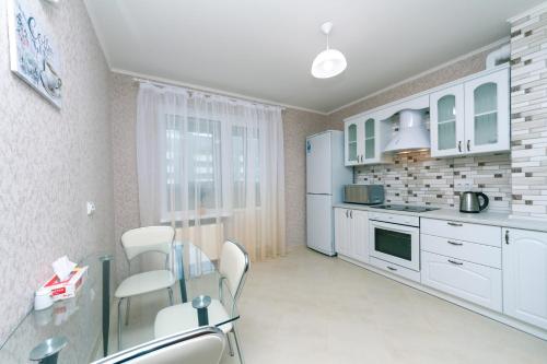 a kitchen with white cabinets and a glass table and chairs at Видовая квартира Yaroslavichi-2 in Vyshhorod