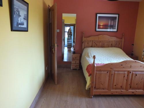 a bedroom with a bed and a woman walking down a hallway at The Burn in Cushendall