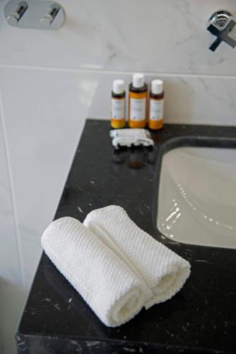 a bathroom sink with a white towel on a counter at Four Streets Athens - Luxury Suites Apartments in Athens in Athens