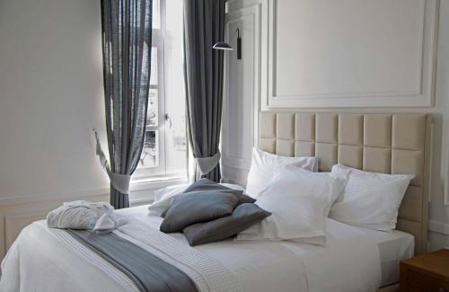 a bedroom with a white bed with pillows and a window at Four Streets Athens - Luxury Suites Apartments in Athens in Athens