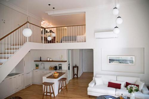a living room with a white couch and a staircase at Four Streets Athens - Luxury Suites Apartments in Athens in Athens