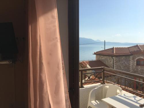 a room with a balcony with a view of the ocean at Chris Studios & Apartments in Lechaio