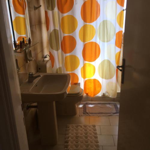 a bathroom with a sink and a toilet and a shower curtain at Chris Studios & Apartments in Lechaio