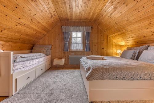 two beds in a room with a wooden ceiling at CHALUPA NA VYHLÍDCE in Jeseník