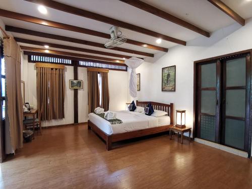 a bedroom with a bed in a room with wooden floors at Tadlo Lodge in Ban Nongtoung