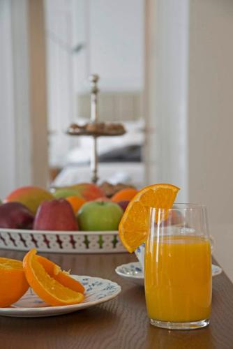 a glass of orange juice sitting on a table with fruit at Four Streets Athens - Luxury Suites Apartments in Athens in Athens