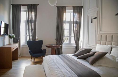 a bedroom with a bed and a chair and windows at Four Streets Athens - Luxury Suites Apartments in Athens in Athens