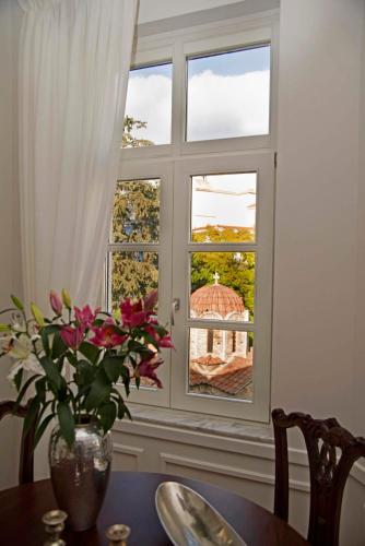 a vase of flowers on a table in front of a window at Four Streets Athens - Luxury Suites Apartments in Athens in Athens