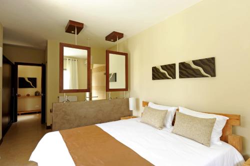 sypialnia z dużym łóżkiem i 2 lustrami w obiekcie Athena Villas by Fine & Country w mieście Grand Baie