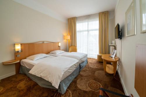 ein Hotelzimmer mit einem großen Bett und einem Fenster in der Unterkunft Grand Hôtel Filippo Strasbourg Nord in Niederbronn-les-Bains