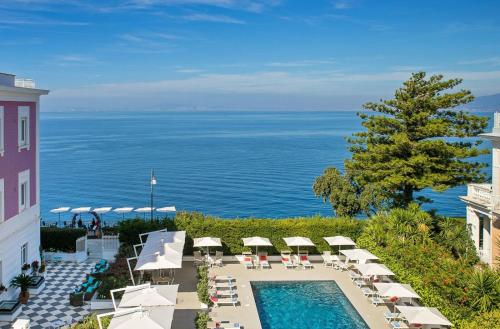 an outdoor pool with umbrellas and chairs and the ocean at Hotel Villa Garden in Sant'Agnello