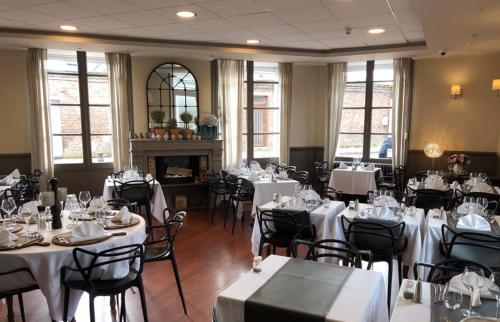 une salle à manger avec des tables et des chaises blanches dans l'établissement La Caroline, à Corbie