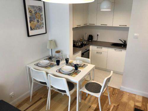 a white dining room table with white chairs and a kitchen at CR Przytulny Apartament przy Pałacu Branickich in Białystok