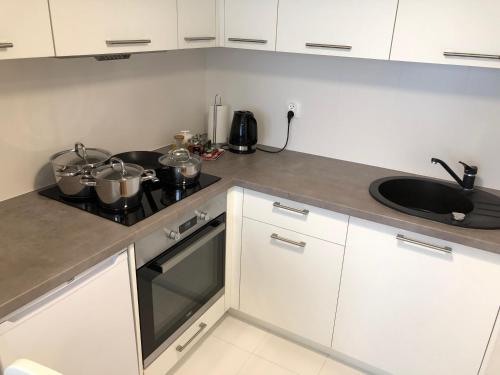 a kitchen with white cabinets and a stove with pots and pans at CR Przytulny Apartament przy Pałacu Branickich in Białystok